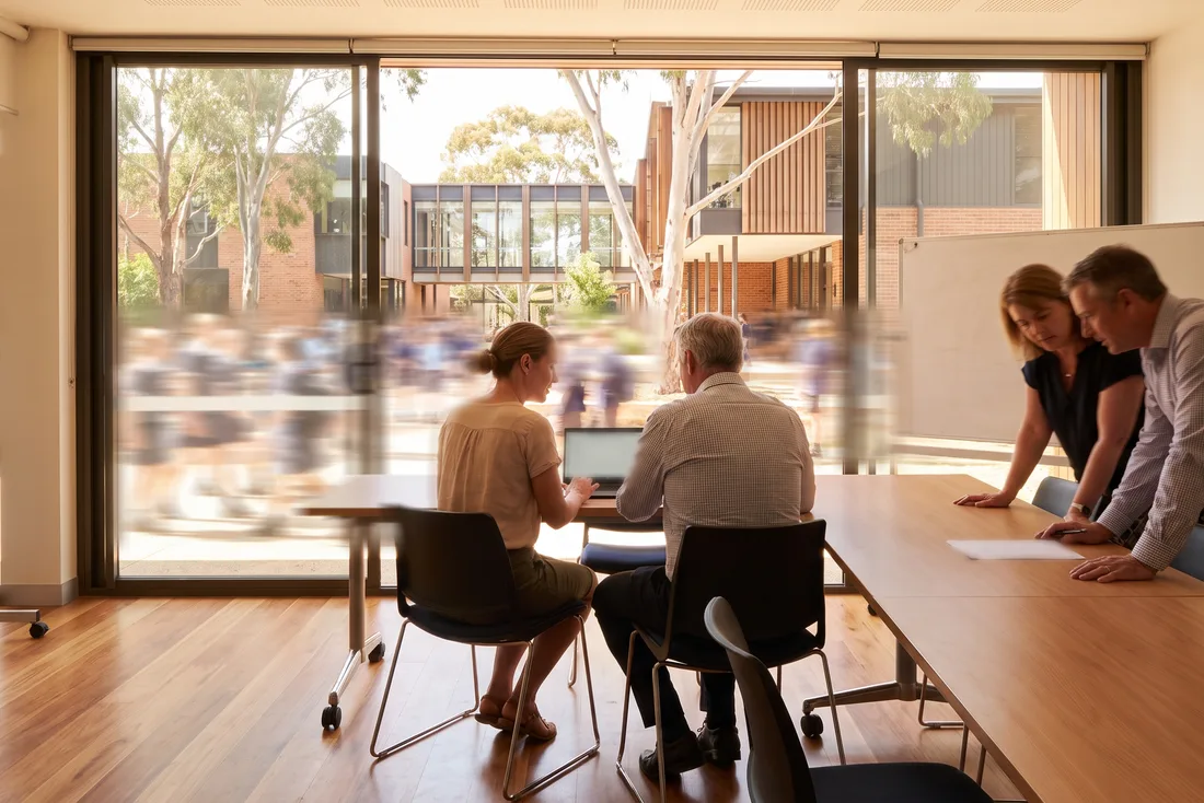 A facilitator and business manager working through a migration with two staff in a bright meeting room.